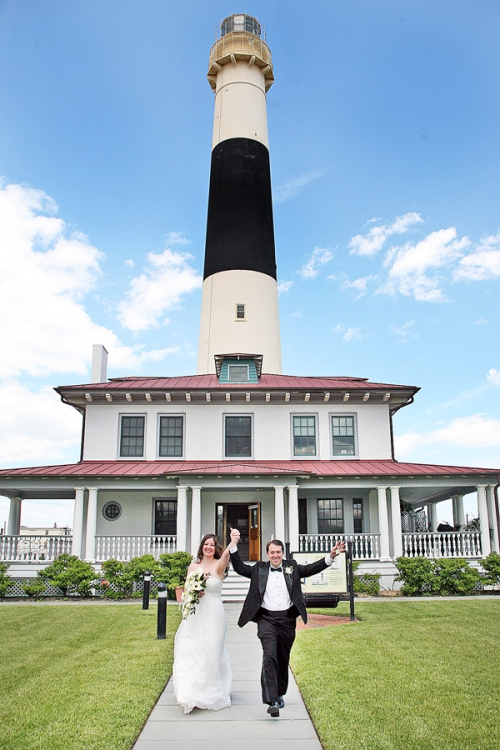 Wedding couple celebrating in front of Barnegat Lighthouse on Long Beach Island near Atlantic City.