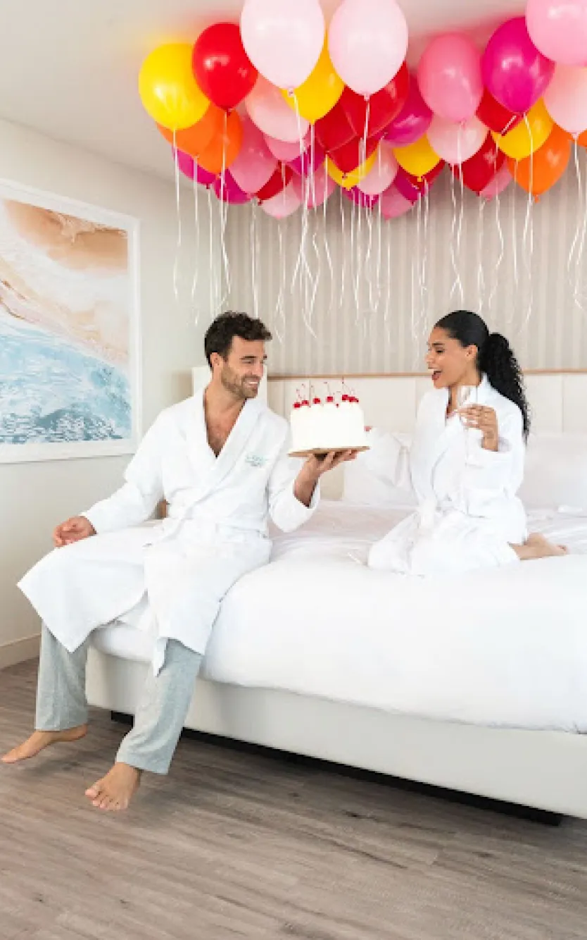 Couple celebrating Ocean Casino Resort’s 7th birthday in Atlantic City with balloons, champagne, and a cake in a luxury suite.