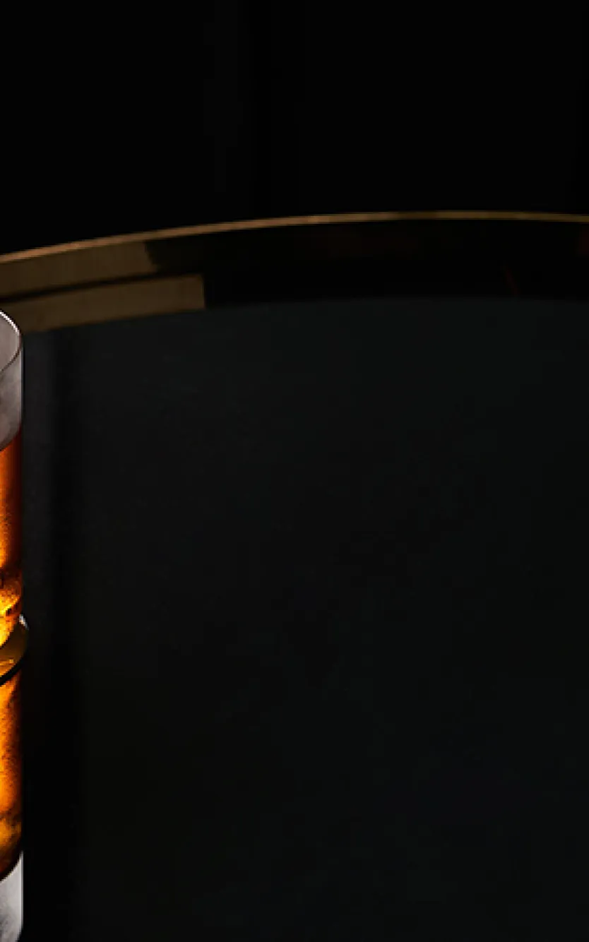 Cocktail sitting on a reflective surface with a dark background and Nola's Bar & Lounge logo on the right