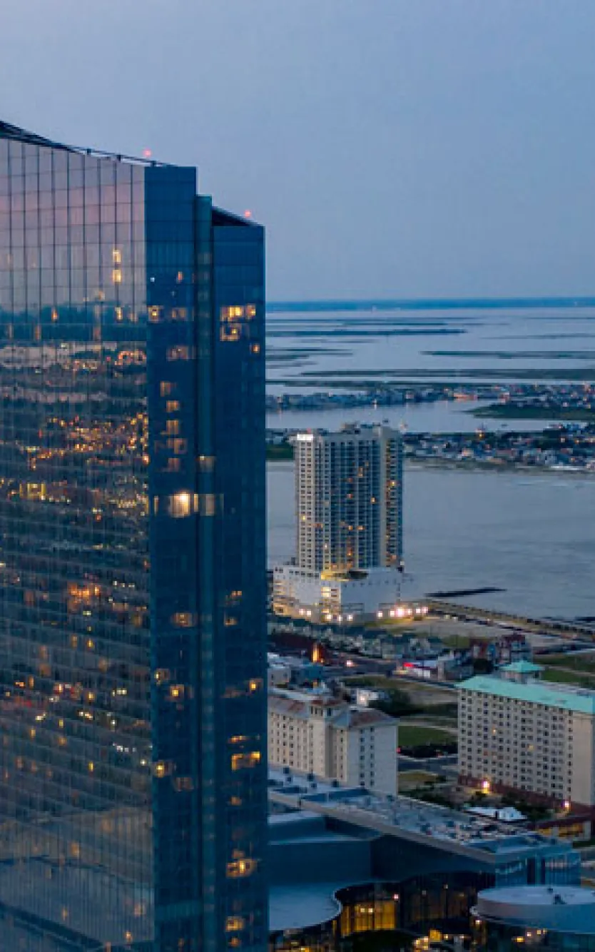 Exterior of Ocean Casino Resort with Atlantic City and water in background in the evening