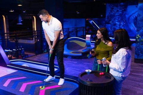 Group of friends toasting drinks at a challenge hole inside Ocean’s 18 Mini Golf & Bar in Atlantic City