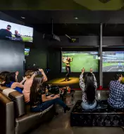 group of adults playing virtual games in the Top Golf Swing Suite