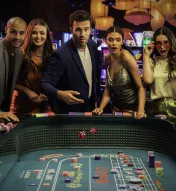 Five stylish guests celebrate a thrilling dice roll at Ocean Casino Resort’s vibrant gaming floor, surrounded by colorful slot machines and glowing lights.