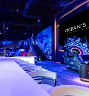Wide view of Ocean’s 18 Mini Golf &amp; Bar featuring neon lighting, underwater-themed décor, and modern bar seating