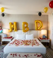 Birthday surprise setup in a hotel room at Ocean Casino Resort with gold balloons and rose petals on the bed