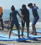 Kids on surf boards at the beach taking surfing lessons