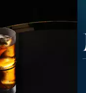 Cocktail sitting on a reflective surface with a dark background and Nola's Bar &amp; Lounge logo on the right