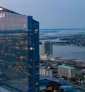 Exterior of Ocean Casino Resort with Atlantic City and water in background in the evening
