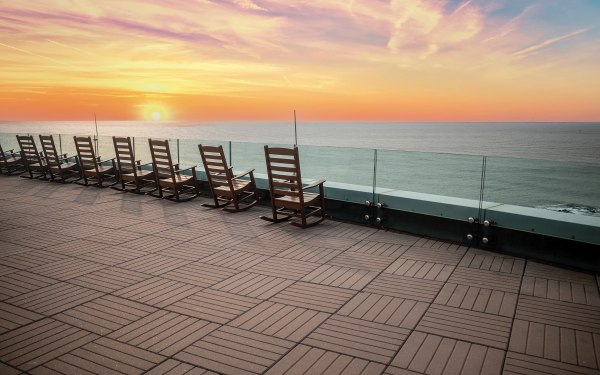 Rocking chairs overlooking the Atlantic Ocean at sunset from The Park at Ocean Casino Resort.