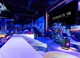 Wide view of Ocean’s 18 Mini Golf &amp; Bar featuring neon lighting, underwater-themed décor, and modern bar seating