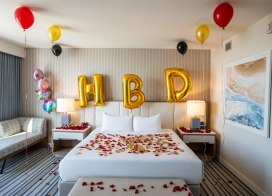 Birthday surprise setup in a hotel room at Ocean Casino Resort with gold balloons and rose petals on the bed